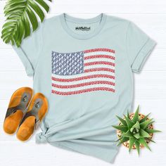 a t - shirt with the american flag on it next to some shoes and plant