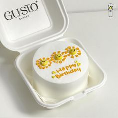 a white cake with yellow flowers on it in a plastic container next to a guso box