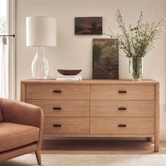 a living room scene with focus on the chest of drawers and flowers in vases