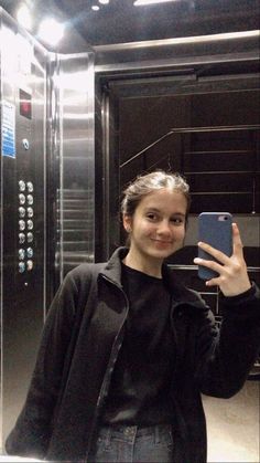 a woman taking a selfie in front of a server room with her cell phone