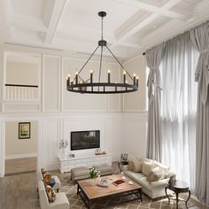 a living room filled with furniture and a chandelier hanging over the top of it