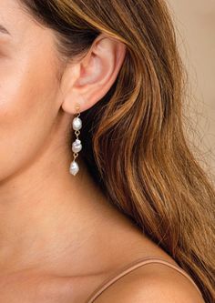 a close up of a person wearing earrings with pearls on the end of their ear