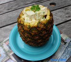 a blue plate topped with a pineapple covered in whipped cream