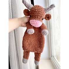 a hand holding up a stuffed animal that looks like a cow with pink nose and tail