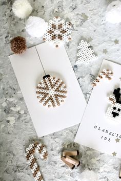 two greeting cards with cross stitch snowflakes on them next to some crafting supplies