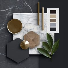 an assortment of items on a marble surface with gold and black accents, such as paintbrushes