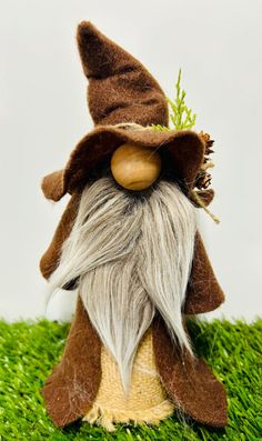 a gnome with long white hair and beard wearing a brown hat on top of green grass