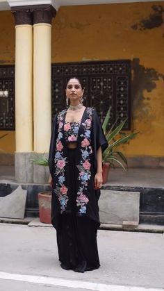 Planning for an upcoming wedding cocktail? Look no further! This exquisite ensemble is designed to make you shine. Introducing the Black Floral Embroidered Patchwork Cape Set, a stunning choice for those seeking elegance in cocktail and party ethnic wear for women. This fashionable cape set showcases beautiful floral embroidery designs that elevate its charm and sophistication. Traditional Silk Palazzo Set With Cape Sleeves, Bohemian Silk Sets With Cape Sleeves, Festival Sets With Resham Embroidery And Cape Sleeves, Traditional Palazzo Set With Cape Sleeves In Georgette, Silk Floor-length Palazzo Set With Floral Embroidery, Traditional Chikankari Embroidery Dress With Cape Sleeves, Party Dupatta With Floral Embroidery And Cape Sleeves, Festive Embroidered Palazzo Set With Cape Sleeves, Embroidered Festival Sets With Cape Sleeves