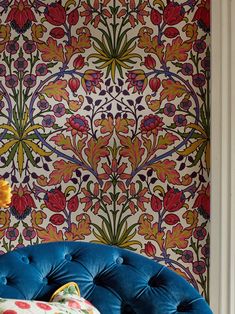 a blue couch sitting in front of a wall covered in colorful floral designs on it's side