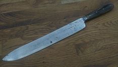 a large knife sitting on top of a wooden table