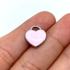 a small pink heart shaped charm on someone's finger