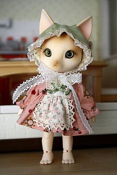 a doll is standing on the floor wearing a dress and bonnet