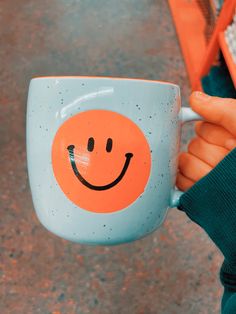 a person holding a coffee cup with a smiley face painted on it