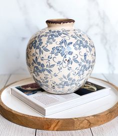 a blue and white vase sitting on top of a wooden tray next to a book