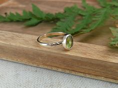 This nature inspired solid gold ring features a beautiful bright green peridot. On one side of the stone the band is adorned with carved leaves, on the other side the band is adorned with a gold ball. The ring band is made out of 1mm thick 14k gold and is about 2 mm wide. Details: - this ring measures a US size 6.25 (16.75mm)  - the peridot measures about 9mm x 6.5mm - the band is approximately 2mm wide and is 1mm thick - the material used recycled 14k solid gold You will receive the exact item as pictured, but please note that colors may vary slightly depending on the screen you are using. This jewel is made with care and much love and will be packaged accordingly. Whether you will buy for yourself or for someone else, the jewel will arrive ready for gifting! All my pieces are handcrafted Dainty Green Peridot Rings, Stackable Green 14k Gold Jewelry, Green Stackable 14k Gold Jewelry, Fine Jewelry Peridot Rings For May Birthstone, Nature-inspired Yellow Gold Gemstone Rings, Stackable Yellow Gold Peridot Jewelry, Green Peridot Stackable Promise Rings, Yellow Gold Peridot Stackable Rings For Anniversary, Green Peridot Stackable Rings