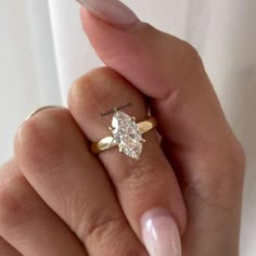 a woman's hand holding a ring with a large diamond on the middle finger