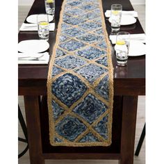 a long table runner with blue and gold designs on the edge, along with white plates