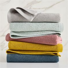 towels stacked on top of each other in various colors and sizes, with one folded