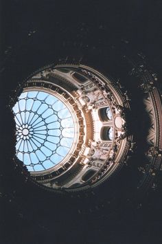 looking up at an ornate glass dome in the center of a building's roof