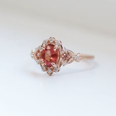 a close up of a ring with an orange stone in the center and white diamonds around it