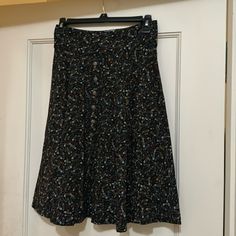 Black Background Skirt With Colorful Safety Pin Pattern. Button Front. 23 Inches Long. Casual Full Skirt Bottoms With Button Closure, Casual Full Skirt With Button Closure, Buttoned Flowy Flared Skirt, Knee-length Flowy Skirt With Buttons, Flowy Knee-length Skirt With Buttons, Flowy Full Skirt With Button Closure, Black Buttoned Skirt, Black Knee-length Skirt With Button Closure, Black Knee-length Bottoms With Buttons