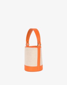 an orange and white handbag on a gray background with the handle extended to show it's inner pocket