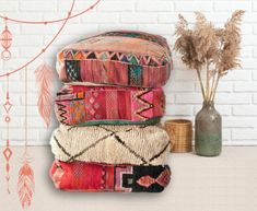 a stack of pillows sitting on top of a table next to a vase