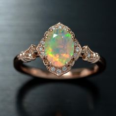 an opal and diamond ring on a black surface