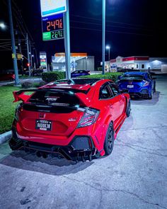 three cars parked in a parking lot next to each other at night with gas prices on the signs