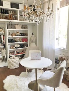 a living room filled with furniture and a chandelier above a white table surrounded by shelves