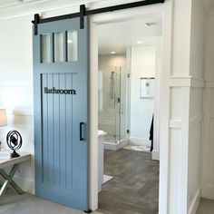 an open door leading to a bathroom with wood flooring and white walls in the background