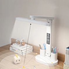 a white desk lamp sitting on top of a wooden table next to a pile of books