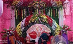 a man sitting on top of a red chair next to a table covered in flowers