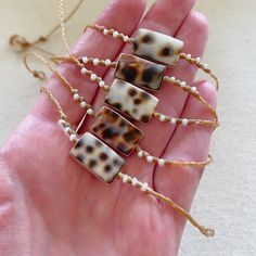 a hand holding four pieces of jewelry in it's palm with pearls and beads