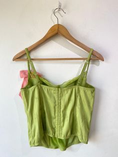 Vintage Victoria’s Secret Lime Green Bustier. A cutesy femme bustier with lace panel going down the front of the bodice and along the tops of the cups. Has boning and underwire. Delicate flower pattern stitched into the silk. Pink bow with circular rhinestone buckle adorning the left strap. In excellent condition. Body is a poly blend, bow is 100% silk. Hand wash cold. Marked size 36B. Approximate Measurements: Cup width: 6" Cup height without lace: 4" Underarm to underarm: 16" Length: 18" Spring Underwire Camisole With Built-in Bra, Spring Camisole With Built-in Underwire Bra, Summer Feminine Underwire Corset, Feminine Underwire Corset For Summer, Spring Underwire Bra-friendly Camisole, Summer Bodice With Underwire Fit, Summer Bodice With Fitted Underwire, Fitted Underwire Bodice For Summer, Feminine Corset With Boned Bodice And Spaghetti Straps