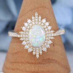 an opal and diamond ring sits on a wooden stand