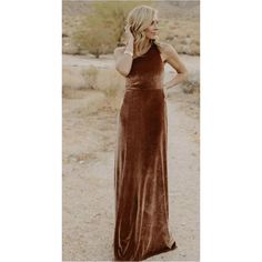 a woman standing in the desert wearing a brown velvet dress with halter neckline