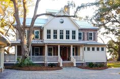 a large white house with lots of windows on the front and side of it's porch