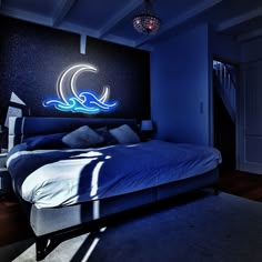 a large bed sitting in a bedroom next to a wall with a neon sign on it