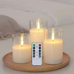 four lit candles with remote control on wooden tray