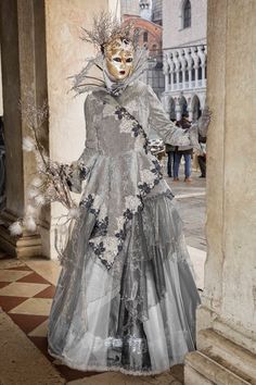 This ornate Venice Carnival mask and costume is very feminine as this female reveler is dressed from head to toe in soft gray and gold.  Her mask is very stoic and it reveals her beautiful eyes.  She wears a headdress of small tree branches and her dress has multiple layers of sheer fabric that reflect the light. Venice Carnival is held in early spring each year and is one of the most anticipated and celebrated events in Europe.  The extravagant costumes and masks are quite memorable and no two Italian Carnival Costumes, Masked Ball Outfit, Venice Mask Carnival, Extravagant Costumes, Venetian Costumes, Venetian Costume, Masquerade Outfit, Venice Carnival Costumes, Italian Home Decor