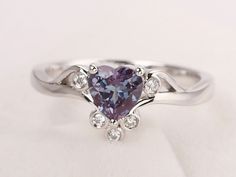 a heart shaped purple diamond ring with diamonds around it