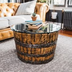 a wooden barrel coffee table sitting on top of a carpeted floor next to a couch