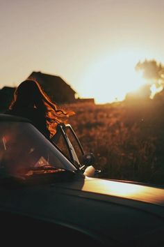 a woman sitting in the back of a car at sunset