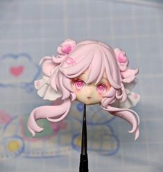 a close up of a doll with pink hair and big eyes on a black stick