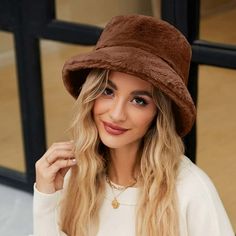 a woman with long blonde hair wearing a brown hat and white sweater is posing for the camera