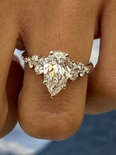 a woman's hand holding a ring with three pear shaped diamonds on top of it