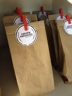 three brown paper bags with red handles and tags on them