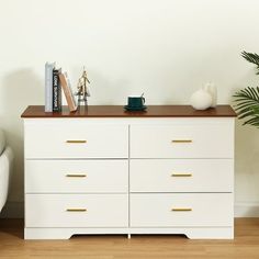 a white dresser sitting next to a couch in a room with a plant on top of it