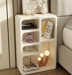 a white shelf with books and other items on it next to a bed in a room